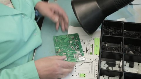 Woman holding pincette and soldering iron install electronic components on PCB (Printed circuit boards)