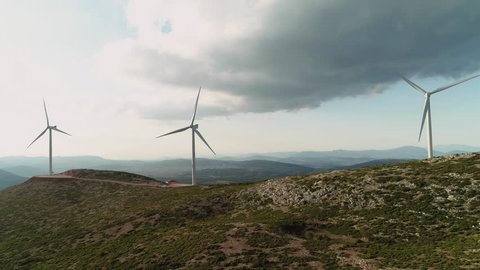 4K Aerial flyby big wind turbines on top of a hill.Aerial establishing shot of a wind farm installation on top of a mountain.