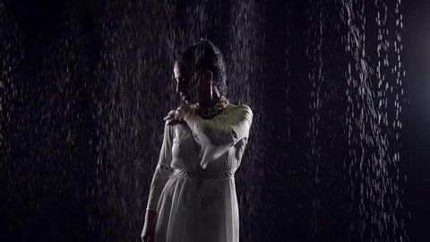 silhouette of woman is standing in black wall background, water flows are falling from above