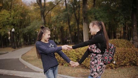 two cheerful friends ride and dance on an electronic scooter in an autumn park.