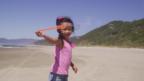 Young girl playing with bubbles at beach Video de stock