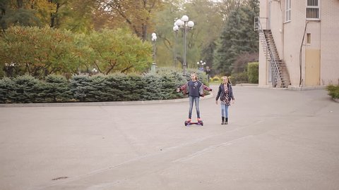 Two girlfriends teenagers have fun. girl drives on an electron gyroscooter in the park
