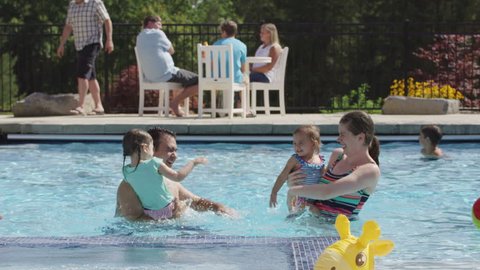 Family playing and splashing in backyard pool
