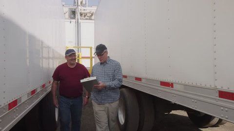 Truck drivers looking over clipboard together. Fully released for commercial use.