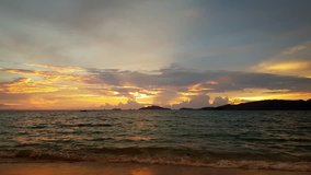 Bright tropical sunset sun rays above the dark sea waves with hilly islands on horizon, 4k UltraHD video
