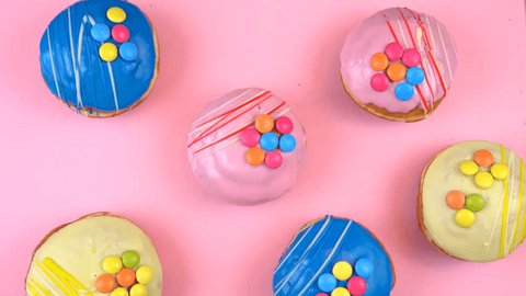 Pop Art Color style donuts and bakery goodies on bright colorful background overhead, time lapse. Vídeo Stock