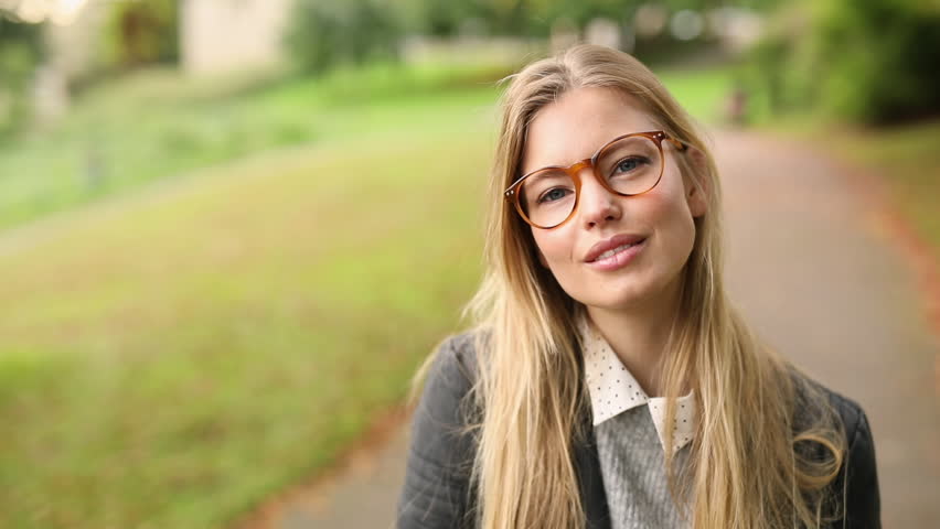 Beautiful girl in glasses smiling to camera in park