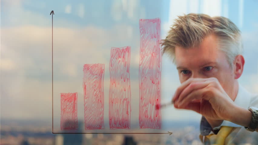 Reflection of a businessman drawing a graph on a window.