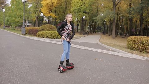 a teenage girl is riding an electronic scooter. the girl dances on gyroscope