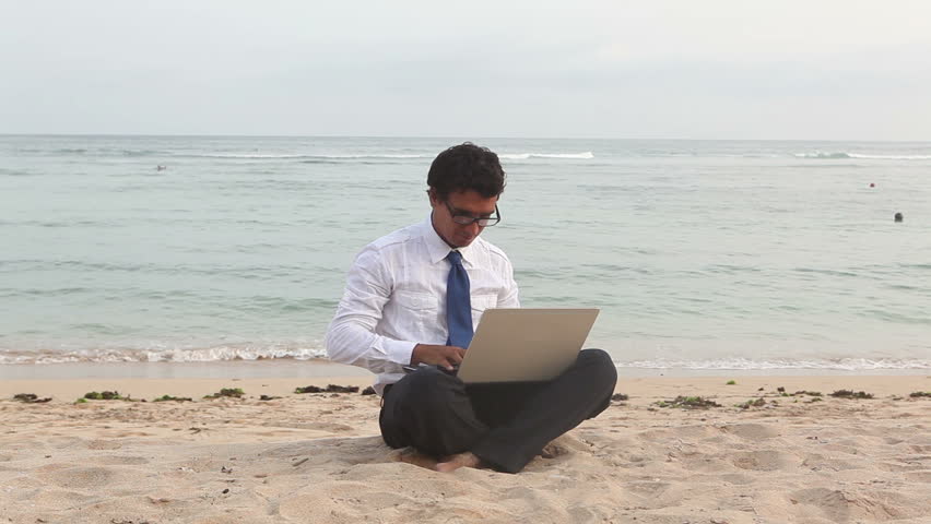 young businessman working on laptop on the beach