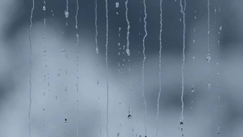 Rain drops running down a window pane. Blue tint.