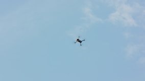 Flying drone with blue sky background, steady in air. Medium. Outdoors. Sunny. Stabilized. No people