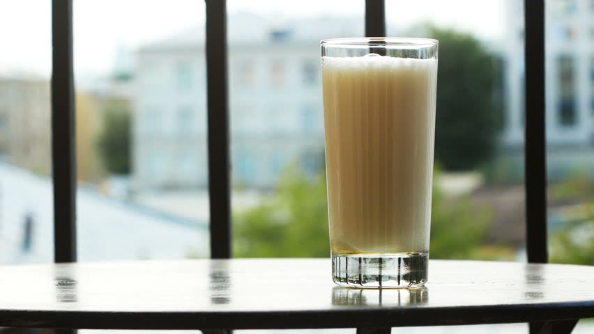 A glass of beer with high foam on the table on the balcony on a summer day