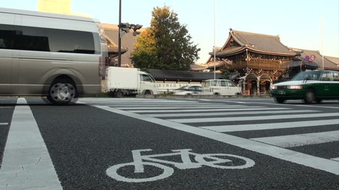 KYOTO, JAPAN - 26 OCTOBER 2012: Cars and other traffic drive past a traditional Japanese temple to provide for a great contrast in the city of Kyoto
