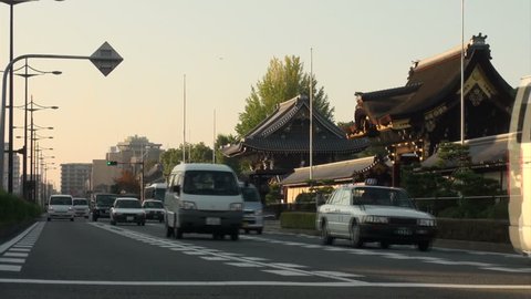 KYOTO, JAPAN - 26 OCTOBER 2012: Cars, vans, motorbikes and other traffic drive past a Buddhist temple on the streets of Kyoto, Japan