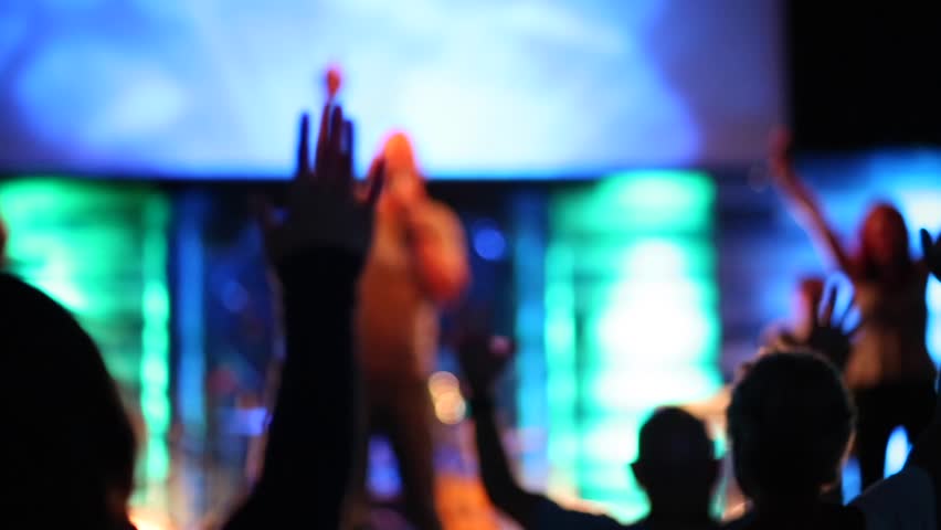 Audience facing facing stage with band holding hand in the air. This is actually a modern church in a worship service. Royalty-Free Stock Footage #31709257