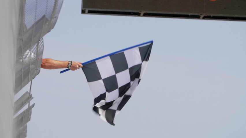 Man holding and waving Checkered race flag in slow motion at finish line on a raceway. Victory, achievement, success and sport concept. | Shutterstock HD Video #31709311