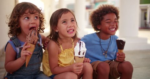 Smiling multi-ethnic children eating ice-cream and having fun together on family summer vacations