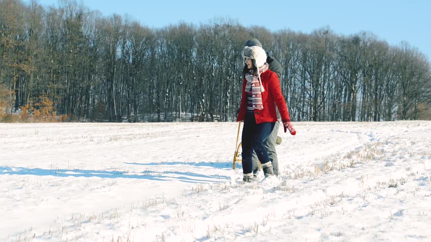 Father and mother pulling daughter on sledge, running.