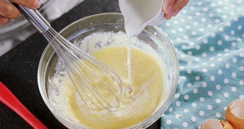 Close-up of woman adding milk to beaten eggs in a bowl 4k