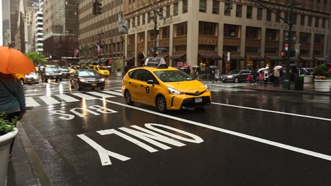 New York-circa 2017: Heavy traffic in the narrow streets of Manhattan, with stunning heights of blocks and bright advertising in the afternoon, on a rainy day, ultra hd4k, real time
