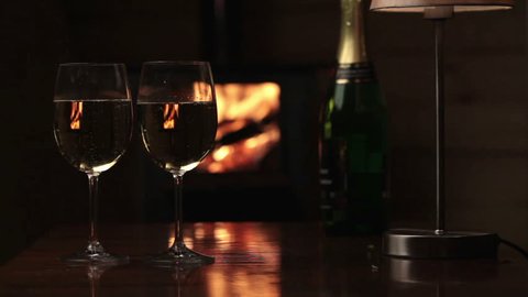 Glasses of champagne near fireplace and candles