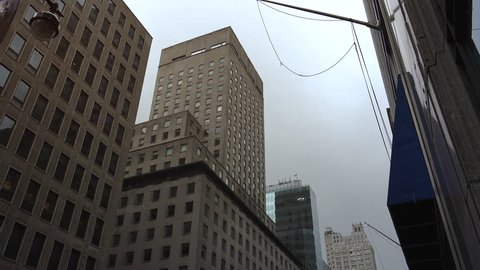 New York-circa 2017: Heavy traffic in the narrow streets of Manhattan, with stunning heights of blocks and bright advertising in the afternoon, on a rainy day, ultra hd4k, real time