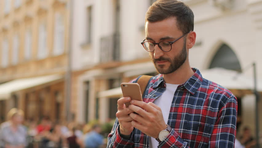 Camera moves around handsome young man as he uses his phone. Portrait. Blurred background Royalty-Free Stock Footage #31725571