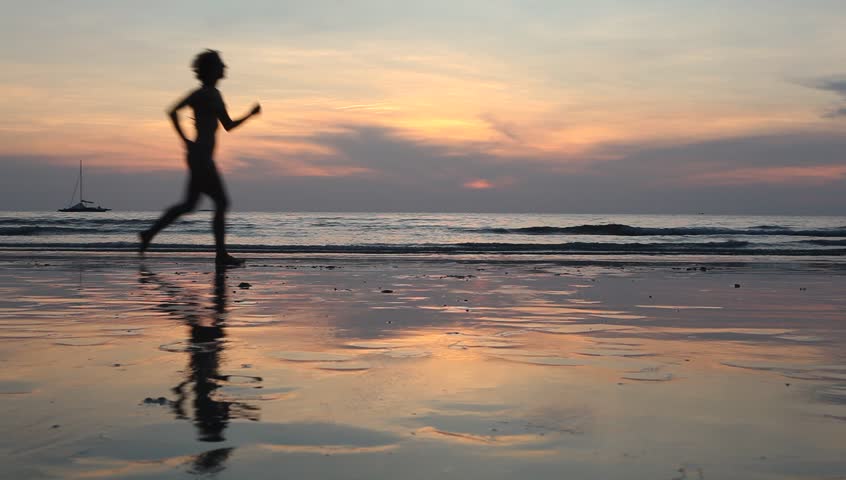 Young woman jogging at sunset on the seashore 