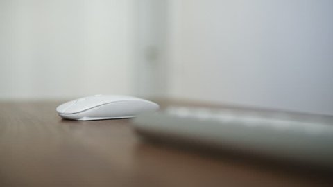Side view of a young man's hand using wireless computer mouse sitting at the table in the office. Wooden table desktop. Shot in 4k
