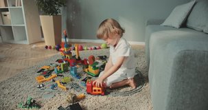 Little cute boy sitting floor enjoying toys at home. Baby designer, game, baby, playing, focused, at home, family, curly hair colored toys r cars children's track Contemporary design.