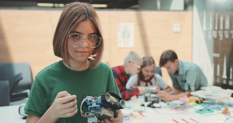 The girl in glasses makes the robot look at the camera, smiles. Contemporary design. Modern toys. Kid, little, office, professional, suit, team. Shot on RED Epic Camera.