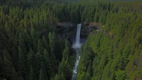 Aerial view of a spectacular waterfall falling down a giant cliff and a river flowing in the canyon. Video taken in Brandywine Falls, near Squamish and Whistler, North of Vancouver, BC, Canada.
