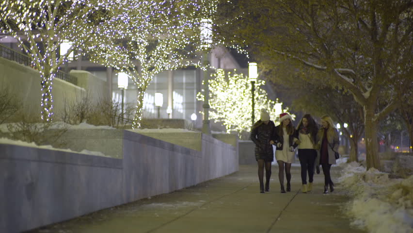 Happy Group Of Friends Walk Arm In Arm Past Christmas Light Display In Downtown Salt Lake City, Utah, USA