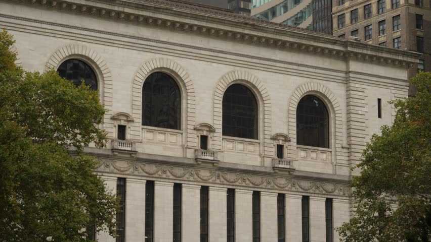 A daytime overcast exterior establishing shot (DX) of the rear facade of the New York Public Library as seen from Bryant Park.  	
