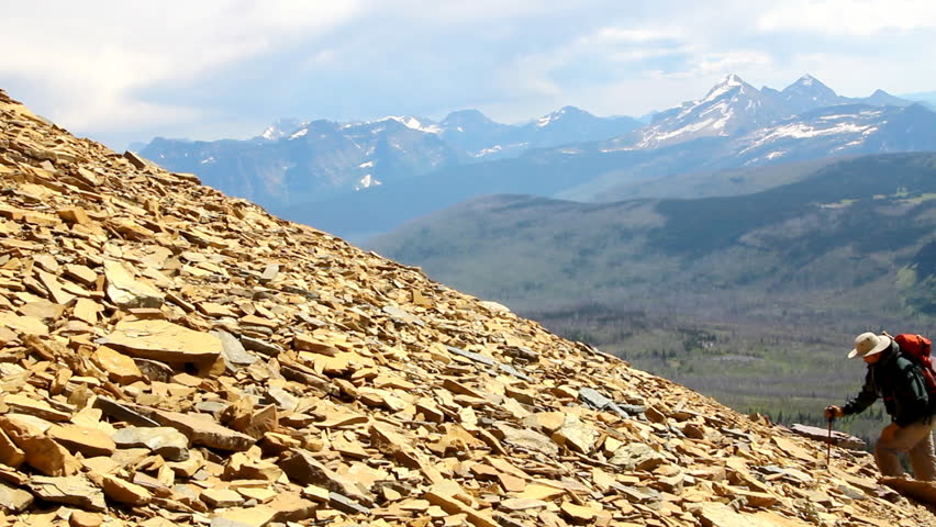 Man climbing up rocks and scree on mountain