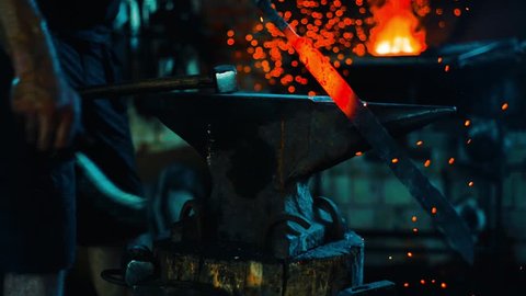 Blacksmith clean off dross from red-hot iron and forge sword blank on anvil 