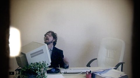 Fake 8mm amateur film: an office worker at work, getting strangled by a hand coming out of the monitor. Rebellion, oppression, workplace, fun.
