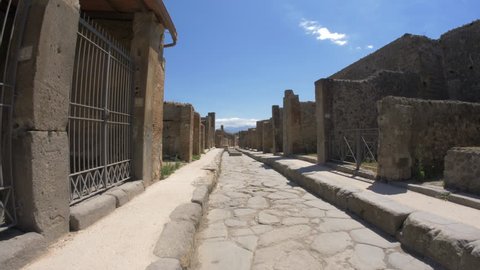 Narrow street of ancient Pompeii are paved with cobblestones with huge stones lying in the middle.