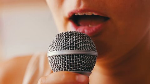 A beautiful girl sing something in a hand-held microphone