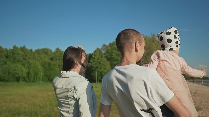 Young family together on the beach with a little daughter. They play with sand. Summer. Recreation. Happy together.