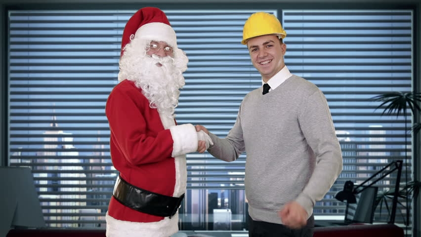 Santa Claus and Young Architect in a modern office, shaking hands and looking at