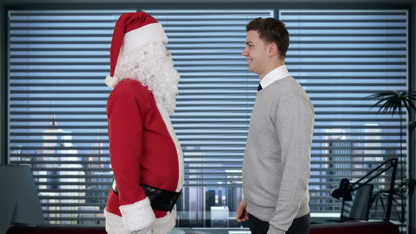 Santa Claus and Young Businessman in a modern office, shaking hands and looking