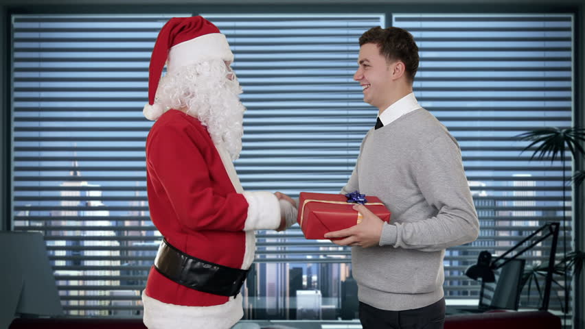 Young Businessman receiving a present from Santa Claus in a modern office,