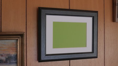 Photo frame hanging on wooden wall, horizontal. Tracking.