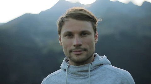 Portrait of man looking at camera face close up outdoors in mountains morning nature. Caucasian handsome confident calm 30s guy with loving kind brown eyes athlete sportsman traveler in grey sweater