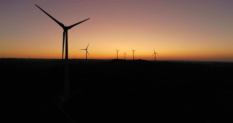 Aerial Wind farm turbines silhouette at sunset. Clean renewable energy power generating windmills. Algarve countryside. Portugal.