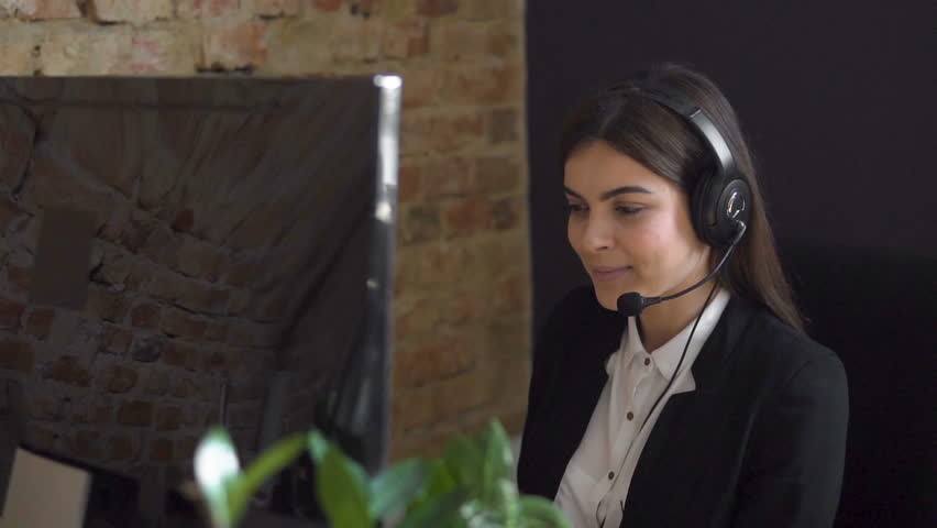 Female operator, in white blouse and black jacket, talking on the headset before the monitor Royalty-Free Stock Footage #31783288