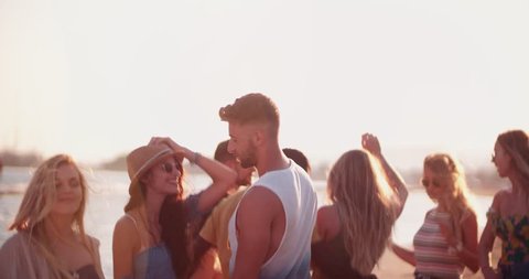 Partying multi-ethnic hipster friends and couples on summer island holidays dancing at beach party