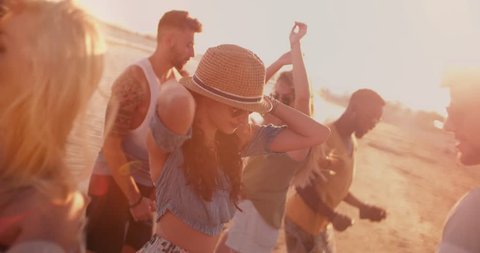 Young multi-ethnic hipster friends and couples dancing and flirting at summer island beach party